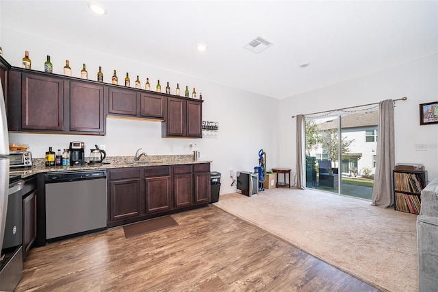 kitchen featuring visible vents, light wood-style flooring, dark brown cabinets, stainless steel dishwasher, and a sink