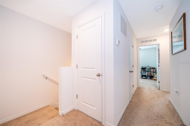 hall featuring light carpet, an upstairs landing, and visible vents