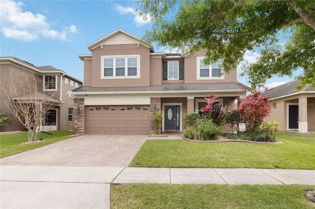 traditional home featuring a garage, stone siding, decorative driveway, stucco siding, and a front yard