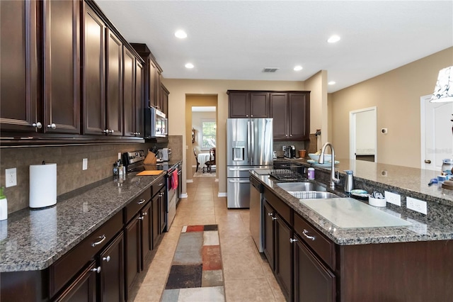 kitchen with appliances with stainless steel finishes, visible vents, a sink, and dark brown cabinetry