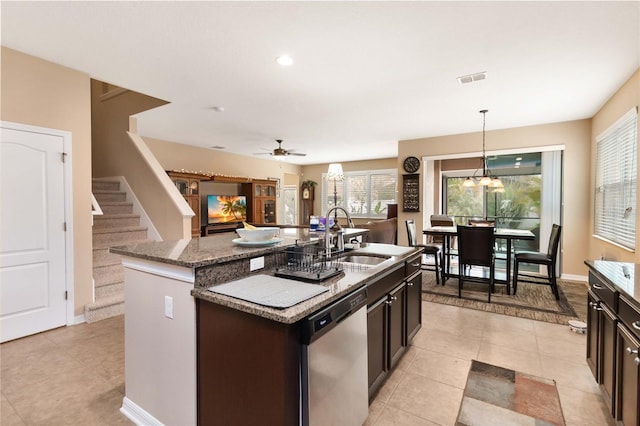 kitchen featuring decorative light fixtures, a center island with sink, light tile patterned flooring, a sink, and dishwasher