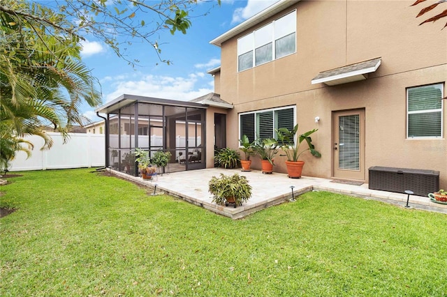 rear view of property featuring a yard, a patio, stucco siding, a sunroom, and fence