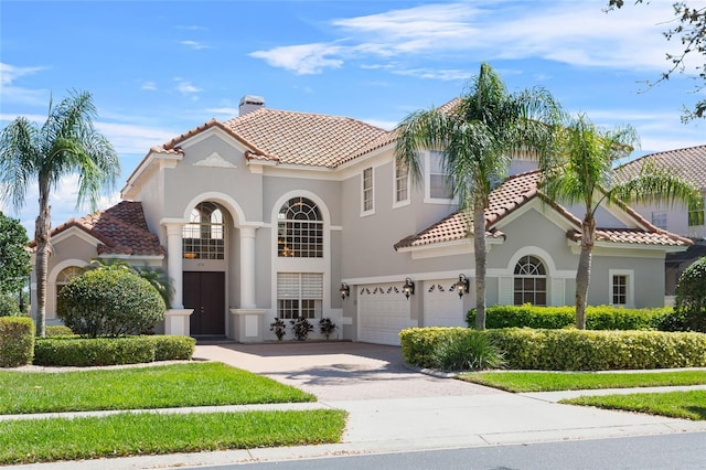 mediterranean / spanish-style home featuring a chimney, stucco siding, concrete driveway, a garage, and a tiled roof