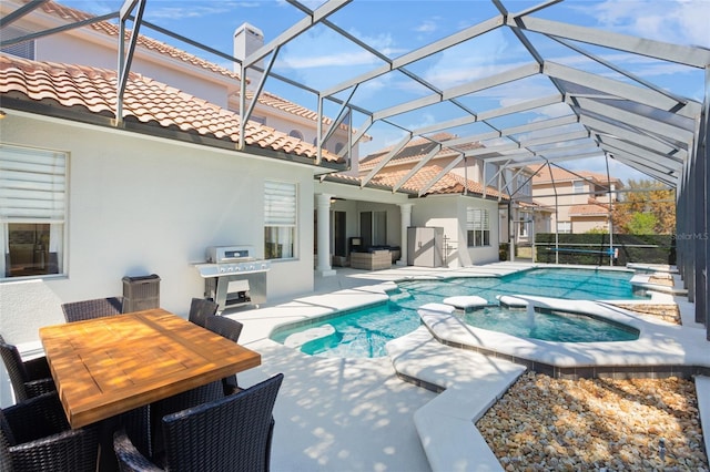 view of pool featuring glass enclosure, a pool with connected hot tub, and a patio