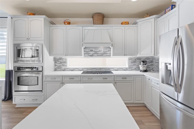 kitchen with stainless steel appliances, light wood-type flooring, white cabinetry, and decorative backsplash