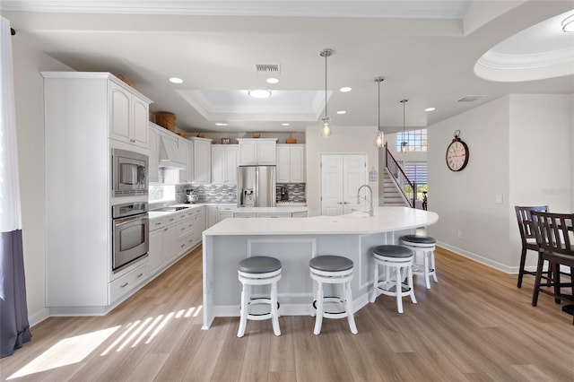 kitchen with visible vents, decorative backsplash, appliances with stainless steel finishes, a tray ceiling, and light countertops