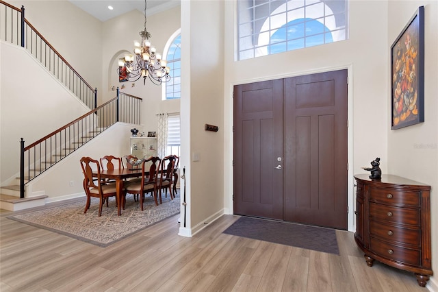 entryway with baseboards, a notable chandelier, stairway, and wood finished floors