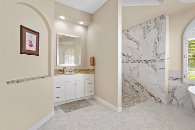 bathroom featuring a marble finish shower, baseboards, a freestanding bath, and vanity