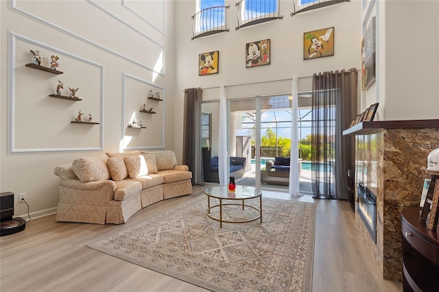 living area featuring a towering ceiling, baseboards, and wood finished floors