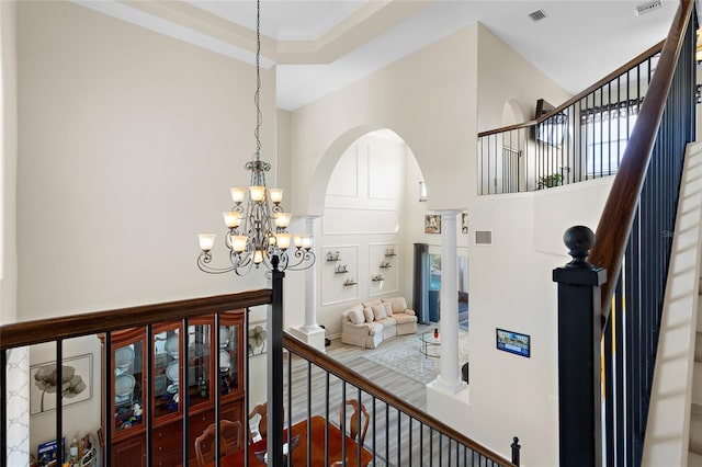 interior space featuring a chandelier, arched walkways, visible vents, and stairway