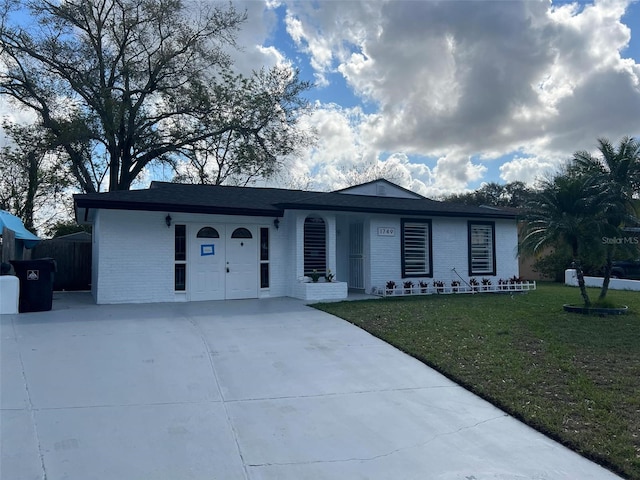 single story home featuring a front yard, brick siding, and driveway