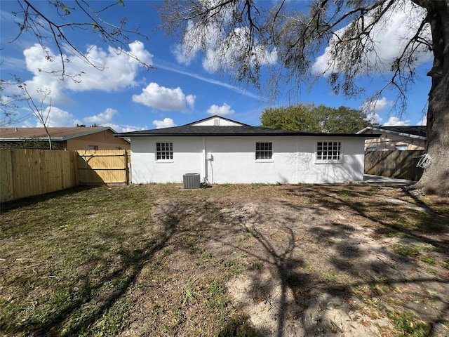 rear view of property featuring central air condition unit, fence, and stucco siding