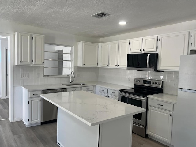 kitchen featuring visible vents, appliances with stainless steel finishes, dark wood-type flooring, and a sink