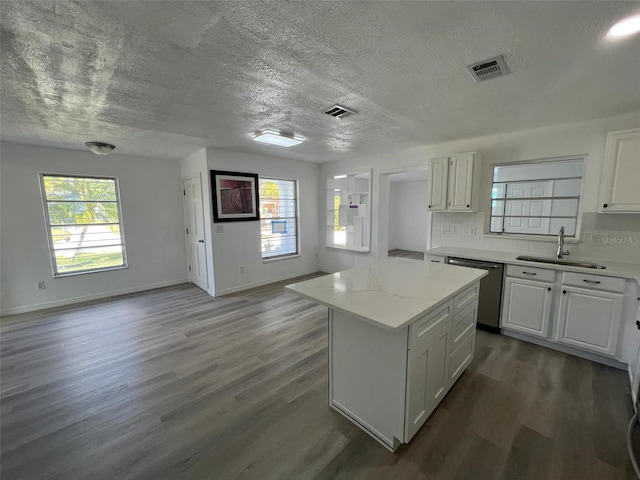 kitchen featuring a center island, stainless steel dishwasher, open floor plan, a sink, and wood finished floors