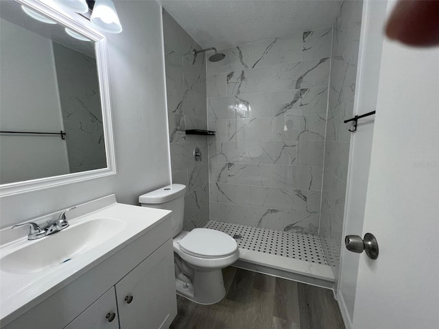 full bathroom featuring toilet, a stall shower, wood finished floors, and vanity