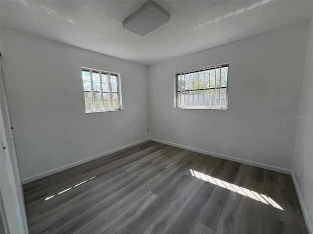 unfurnished room featuring a wealth of natural light, baseboards, and wood finished floors