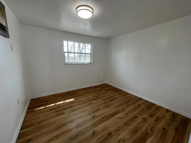 empty room featuring wood finished floors and baseboards