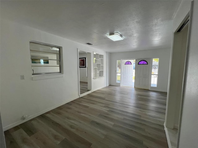 spare room featuring a textured ceiling, wood finished floors, visible vents, baseboards, and built in features