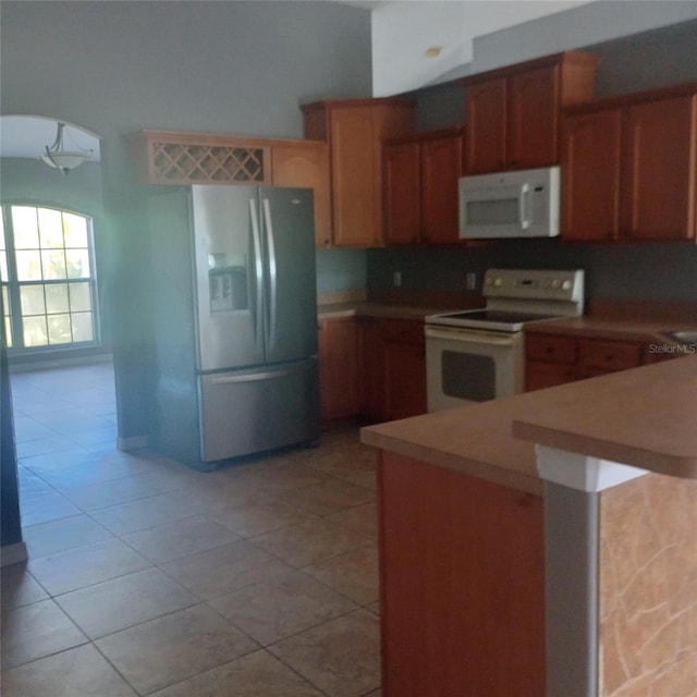 kitchen with white appliances, light tile patterned floors, light countertops, and arched walkways