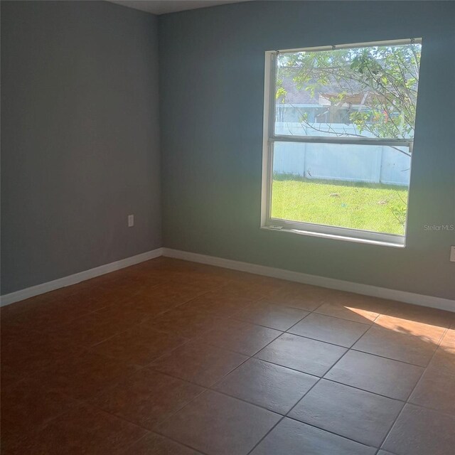 tiled empty room featuring baseboards