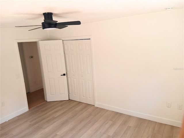 unfurnished bedroom featuring light wood-style flooring, baseboards, and a closet