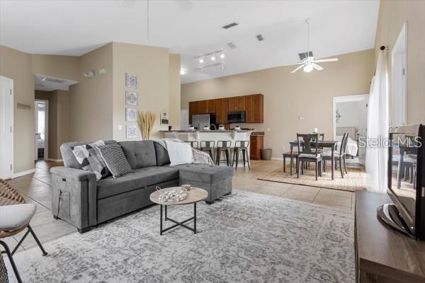 living area with a ceiling fan, light tile patterned flooring, visible vents, and baseboards