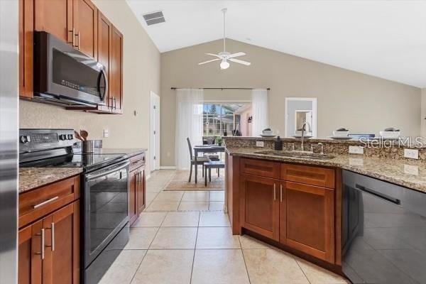 kitchen featuring stone counters, stainless steel appliances, a sink, visible vents, and vaulted ceiling