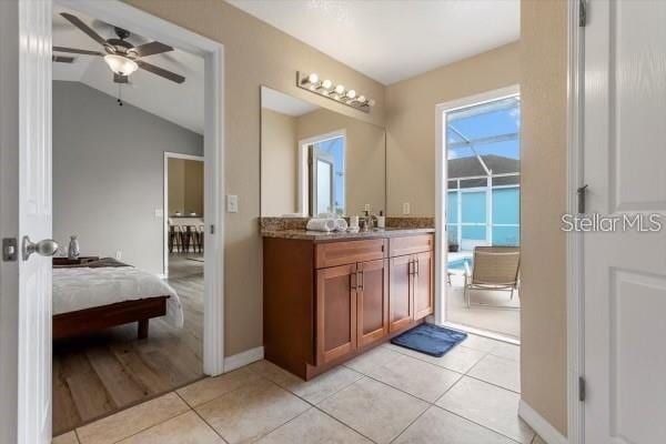 ensuite bathroom with lofted ceiling, vanity, ensuite bath, tile patterned flooring, and baseboards