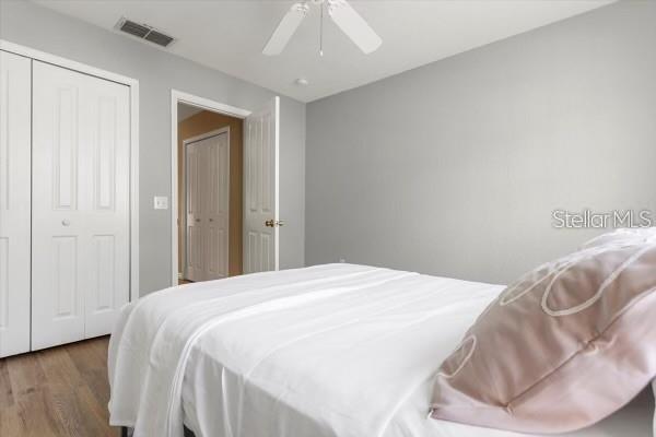 bedroom with ceiling fan, a closet, visible vents, and wood finished floors