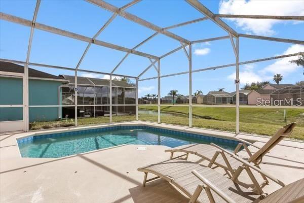 pool featuring a patio, a yard, and glass enclosure