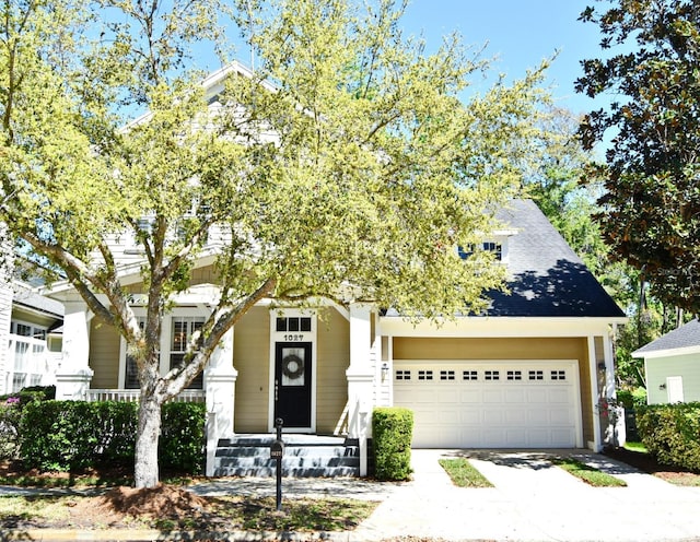 view of property hidden behind natural elements with driveway, a shingled roof, and a garage