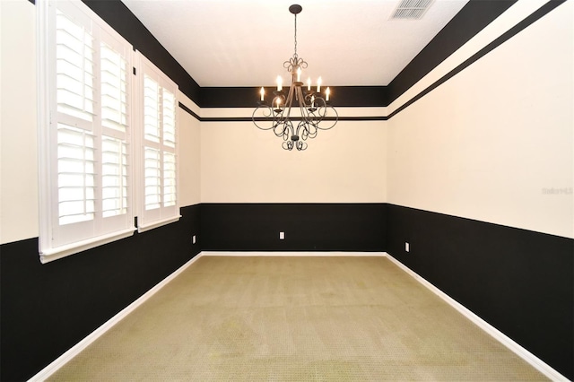 carpeted empty room with visible vents, baseboards, and an inviting chandelier