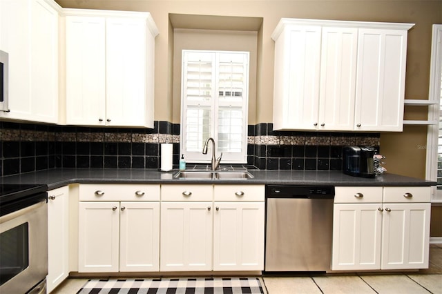 kitchen featuring a sink, dark countertops, white cabinets, and stainless steel appliances