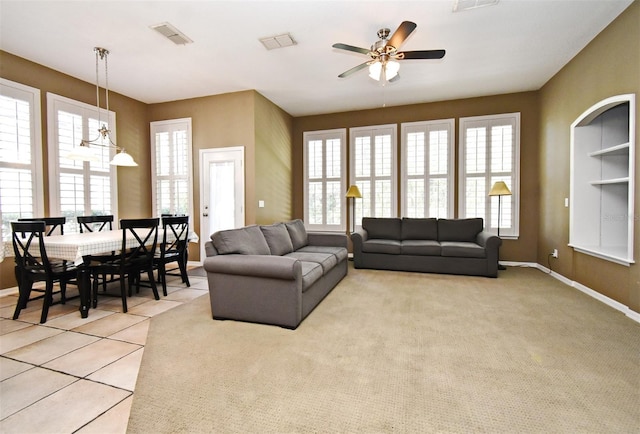 living area featuring visible vents, light carpet, and baseboards