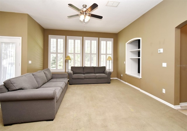 living area with visible vents, light carpet, baseboards, and a ceiling fan