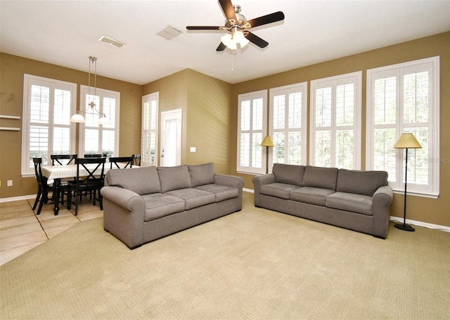 carpeted living area featuring tile patterned floors, visible vents, a ceiling fan, and baseboards