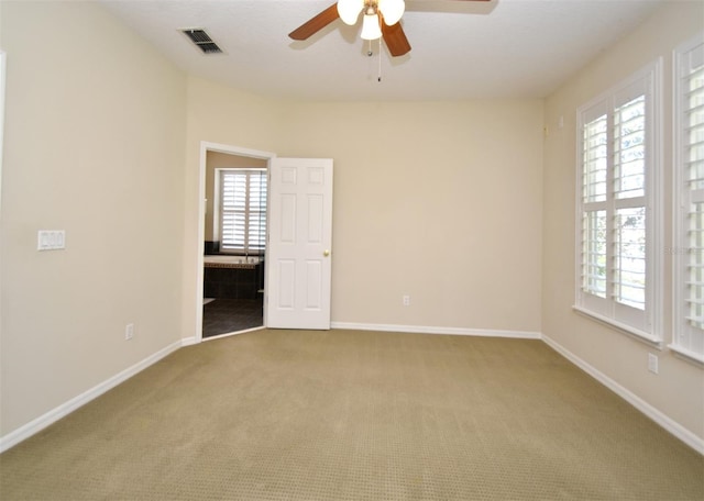 spare room with a wealth of natural light, carpet flooring, visible vents, and baseboards