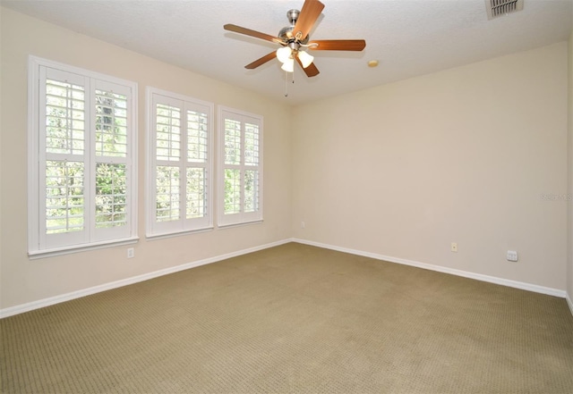 carpeted spare room featuring visible vents, a ceiling fan, and baseboards