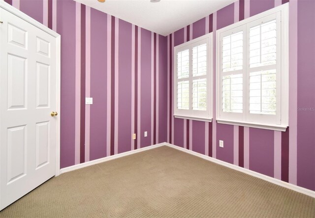 empty room with wallpapered walls, carpet flooring, and baseboards