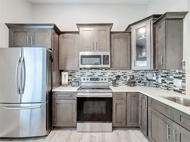 kitchen featuring appliances with stainless steel finishes, light countertops, light wood-style floors, and backsplash