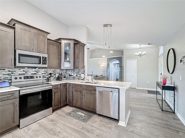 kitchen featuring stainless steel appliances, light countertops, a sink, and dark brown cabinetry