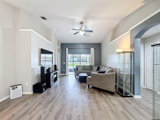 living room with arched walkways, visible vents, lofted ceiling, and wood finished floors