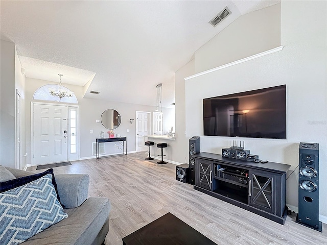 living room with visible vents, vaulted ceiling, baseboards, and wood finished floors