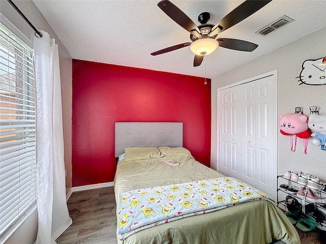 bedroom featuring a closet, visible vents, a textured ceiling, wood finished floors, and baseboards