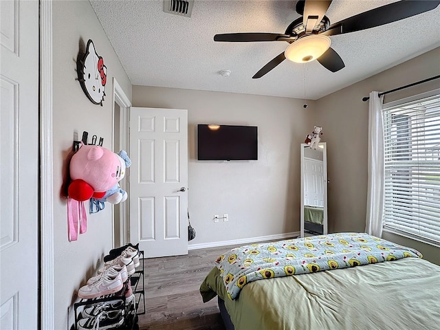 bedroom featuring baseboards, visible vents, ceiling fan, wood finished floors, and a textured ceiling