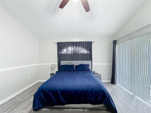 bedroom featuring baseboards, lofted ceiling, ceiling fan, wood finished floors, and a textured ceiling