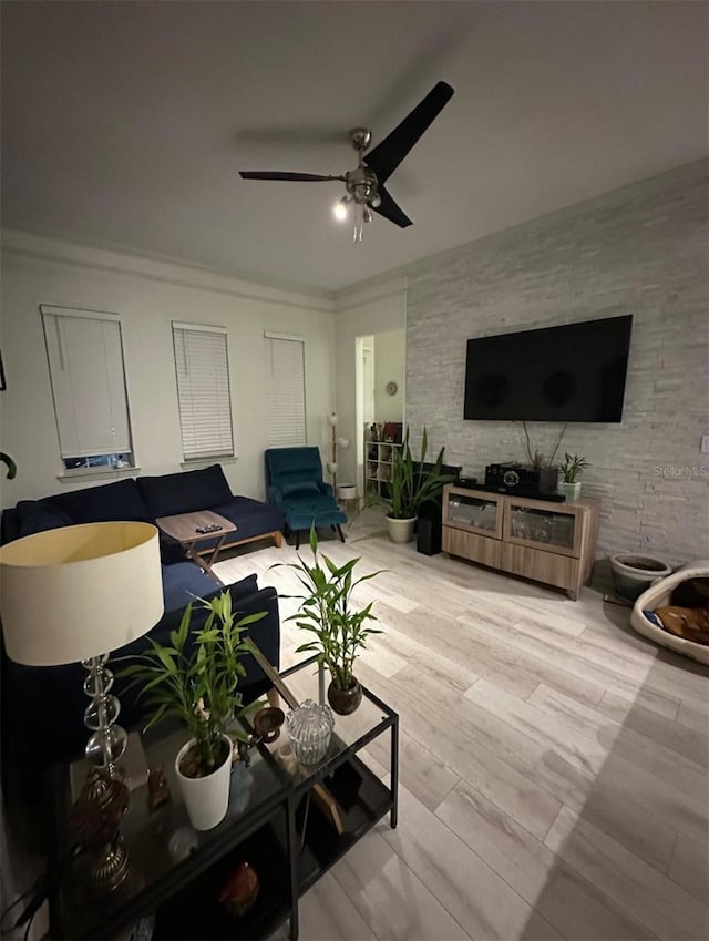 living area with wood finished floors, ceiling fan, and ornamental molding