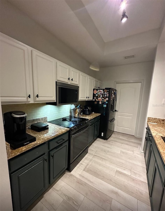 kitchen with decorative backsplash, light stone countertops, black appliances, and white cabinetry