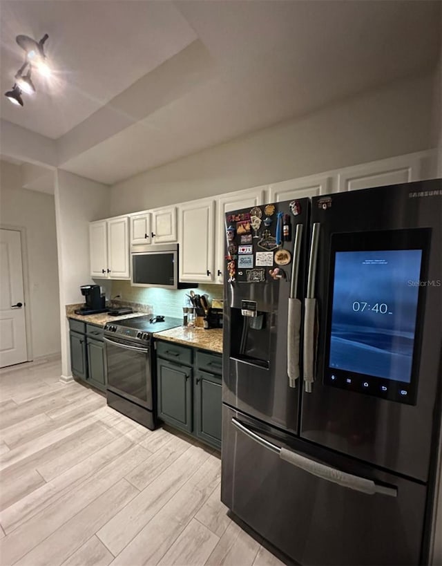 kitchen featuring range with electric cooktop, refrigerator with ice dispenser, stainless steel microwave, white cabinetry, and light wood-style floors