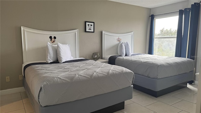 bedroom with a textured ceiling, light tile patterned flooring, and baseboards